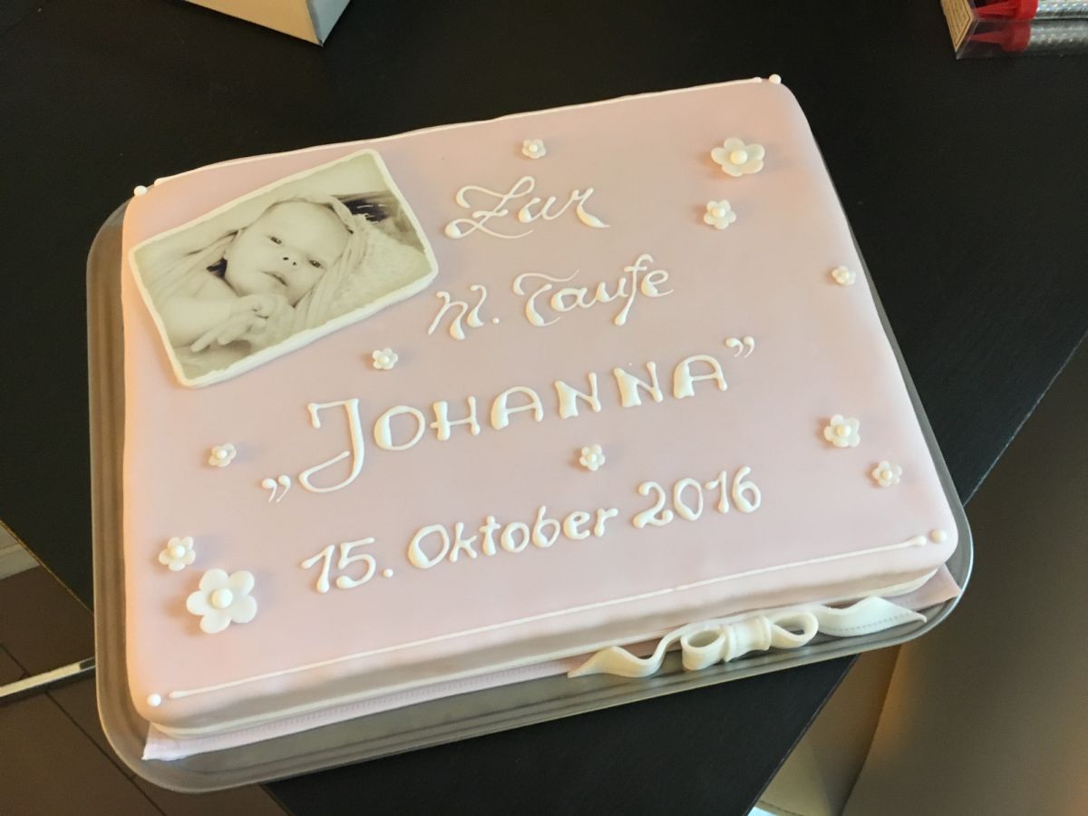 Pink christening cake with baby photograph and white sugar flowers