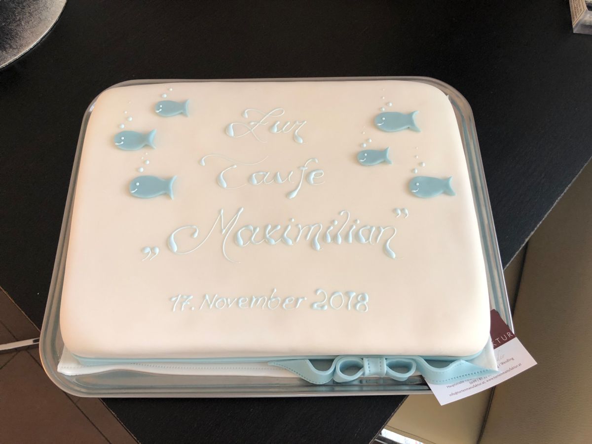 White christening cake decorated with five turquoise fish and pearls