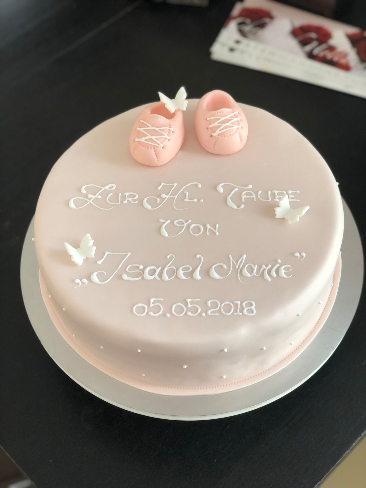 Christening cake topped with lace-patterned booties and white doves