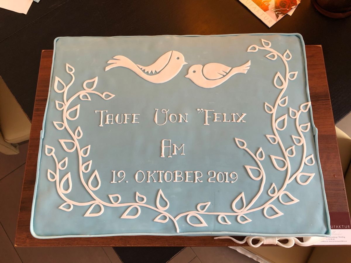 Light blue christening cake with two white doves and leaf wreath