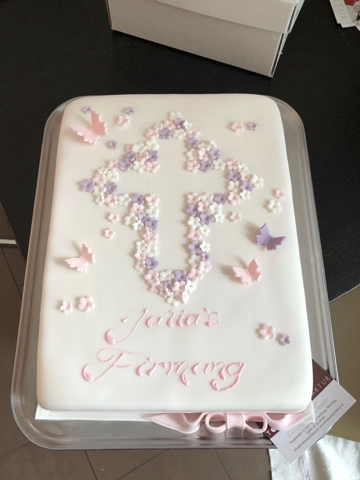 White christening cake with cross of flowers and butterfly decorations