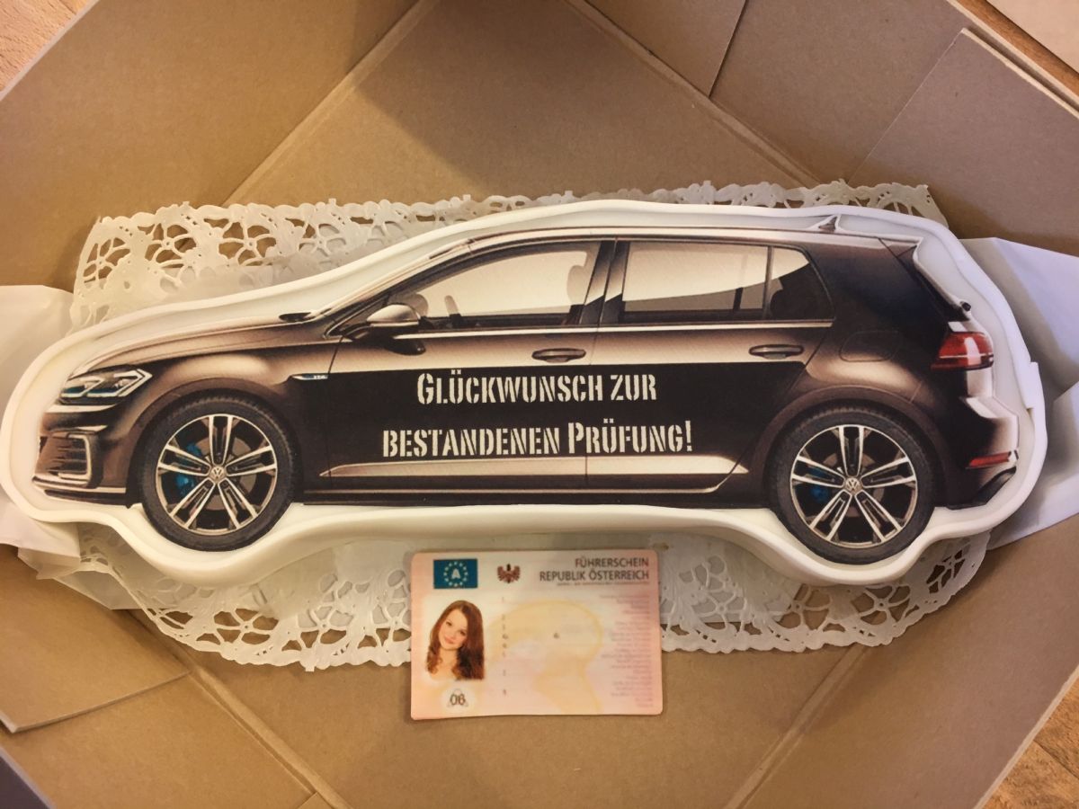 Black VW Golf-shaped cake with gold wheels and driving test congratulations message