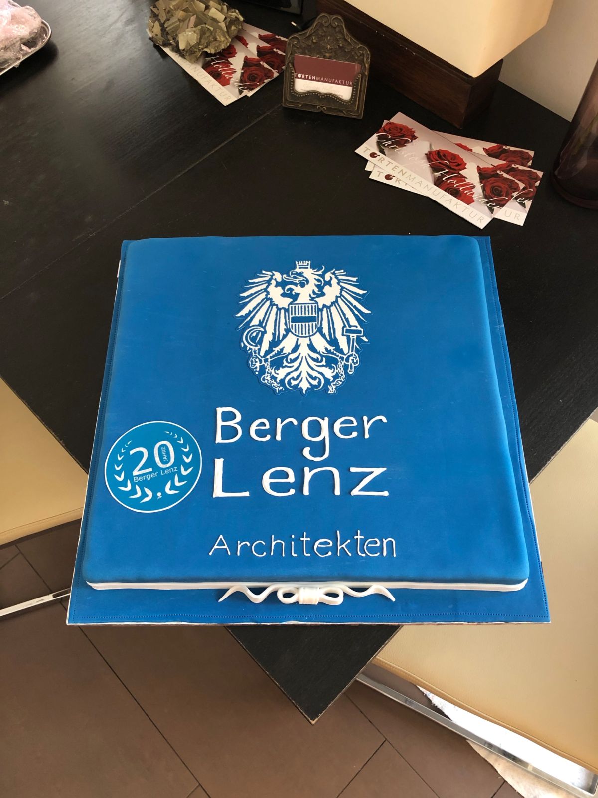 Square blue anniversary cake for Berger Lenz Architekten with eagle emblem and 20-year seal